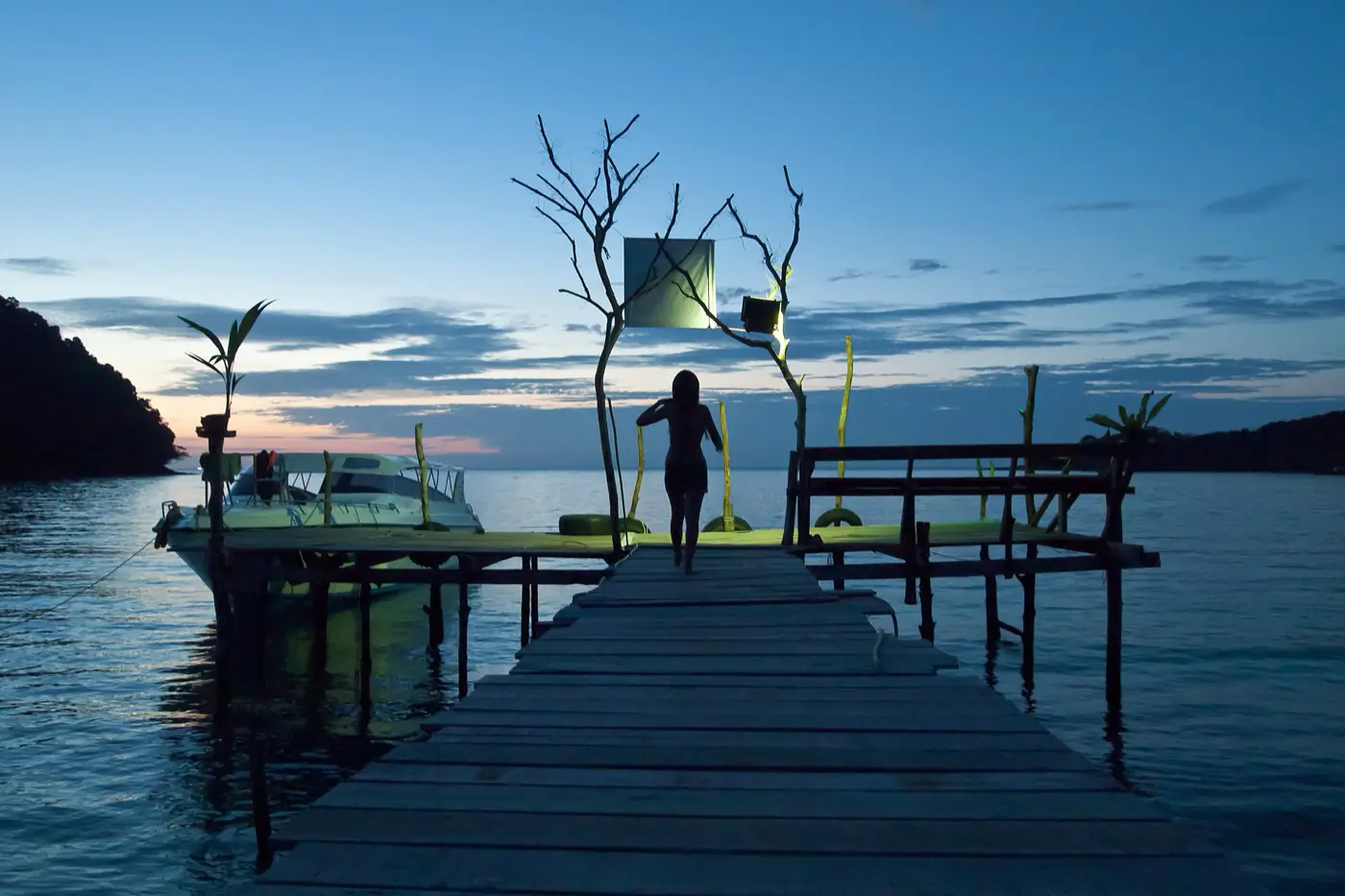A wooden pier reaching into calm water at twilight on Ko Kut