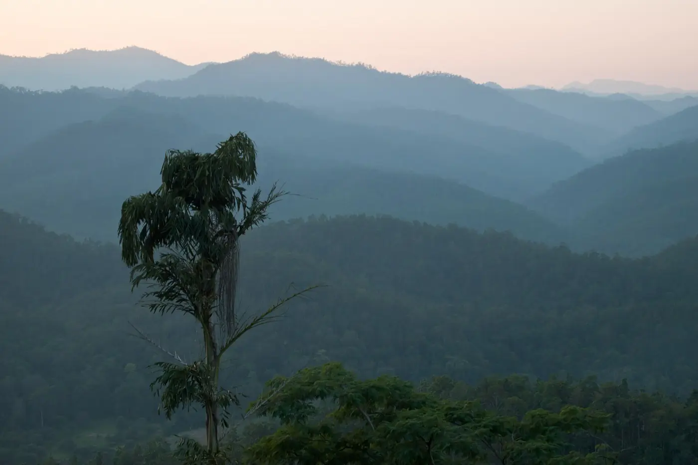 Layered forested ridges fading into haze at twilight in Mae Hong Son