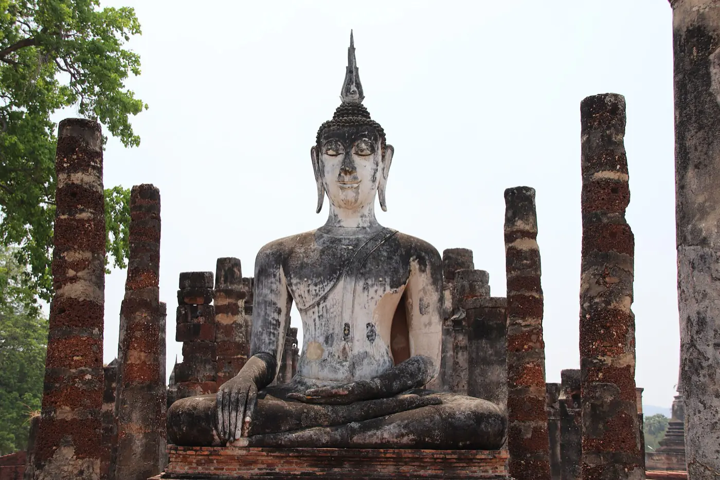 A seated stone Buddha among brick columns at Wat Chana Songkhram, Sukhothai