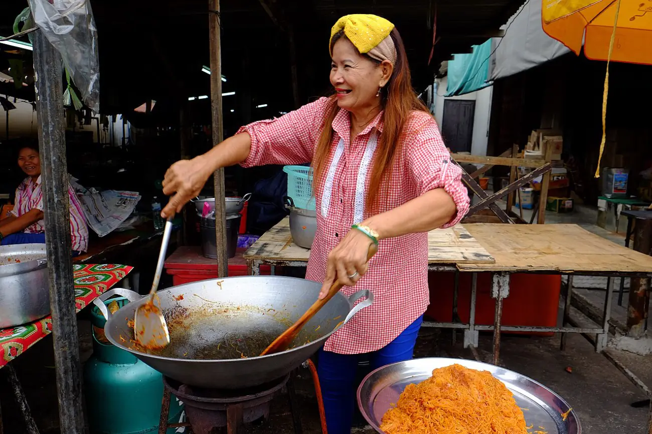 A street cook working a wok over a burner at a roadside stall