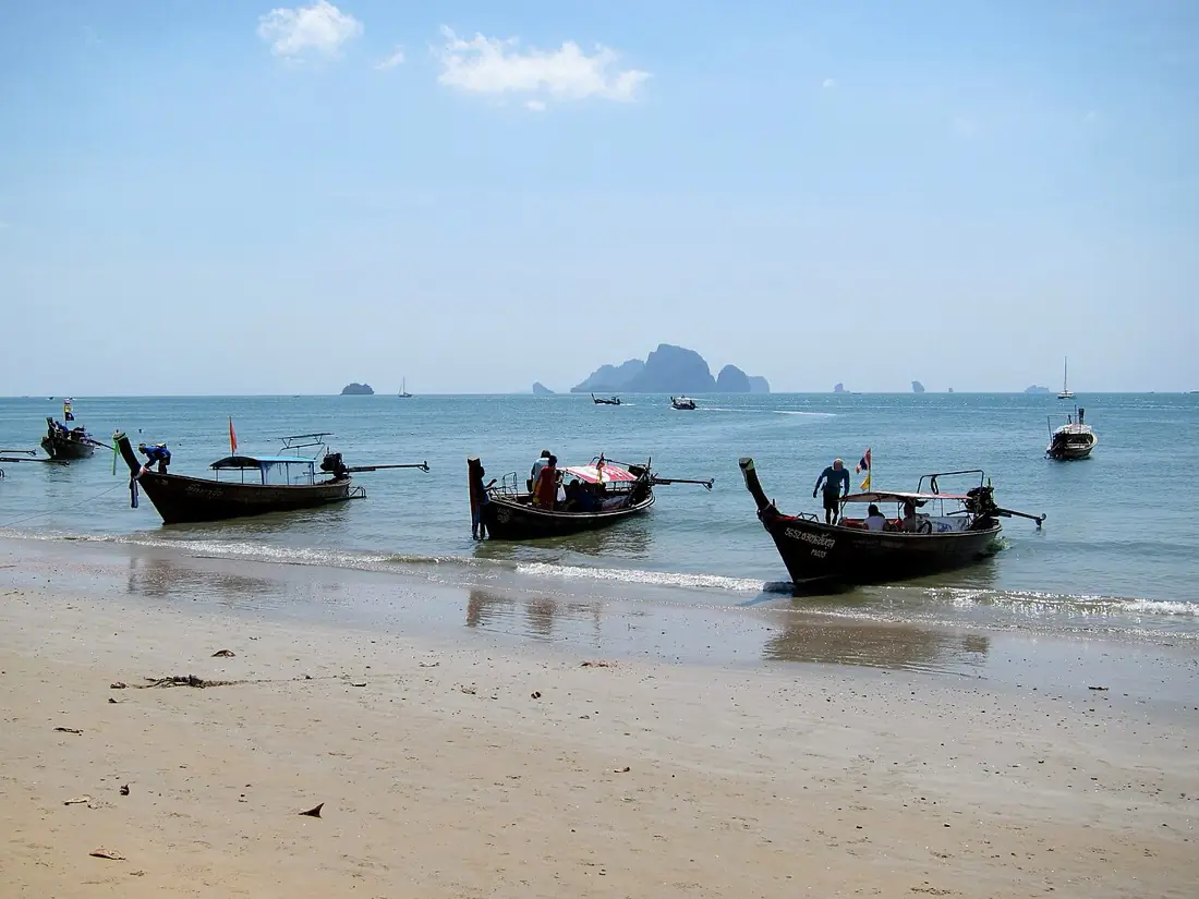 Wooden longtail boats moored in turquoise shallows off Ao Nang beach, Krabi